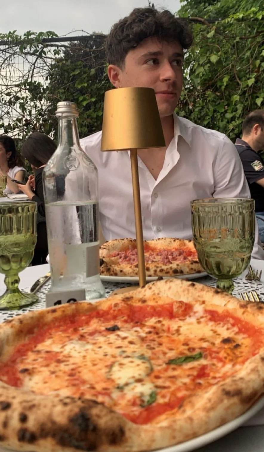 una persona seduta a un tavolo con pizza e vino